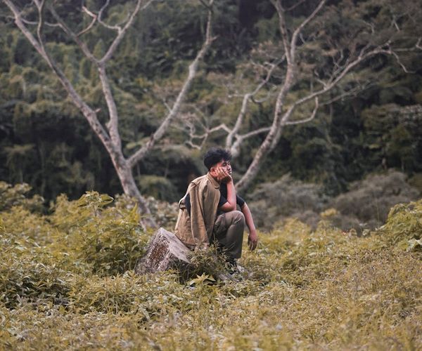Man meditating outdoors with a serene landscape background.